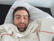 Menneske ligger under dynen og sover