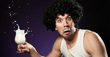 Mand, med mælkeskæg med et glas mælk i hånden, som ser meget skræmt ud.