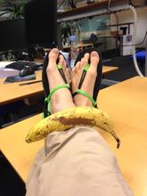 Fødder iklædt sandaler på kontoret - en banan ligger også på fødderne